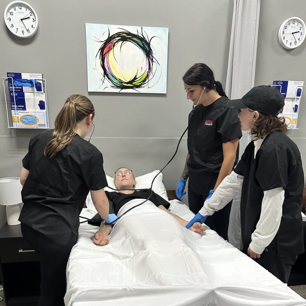 Three medical professionals standing around a patient who is lying down on a bed